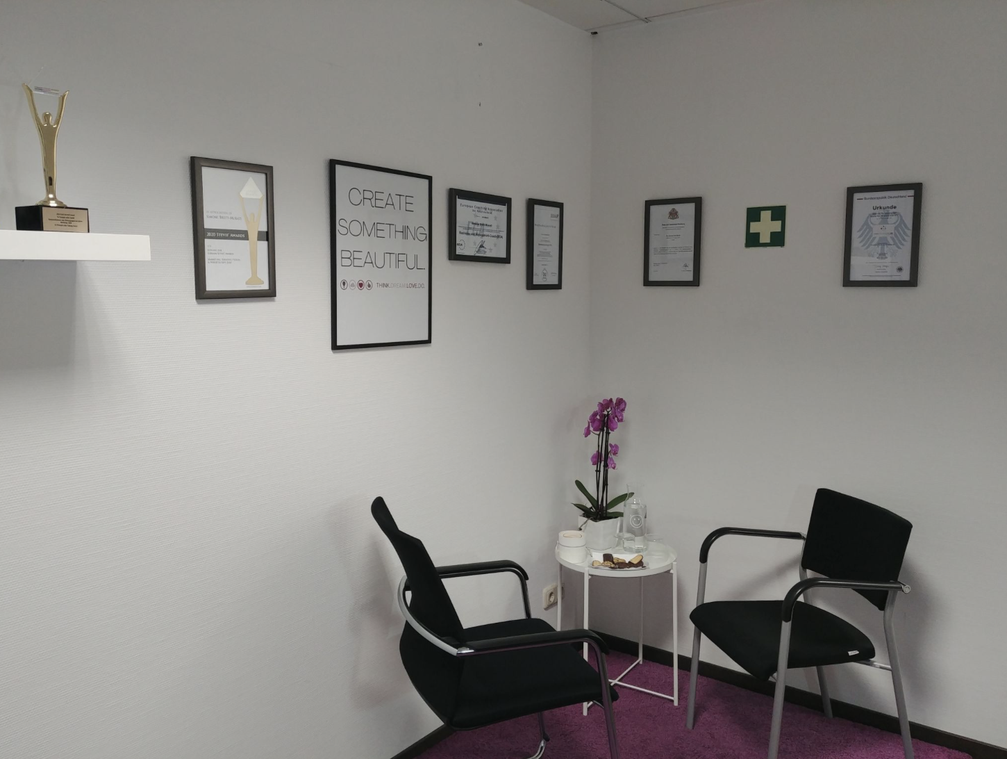 Büroraum mit einem Tisch und zwei Stühlen in der Ecke, an der Wand hängen Zertifikate